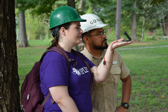 A woman gesturing in a direction with a man looking besider her looking in that direction