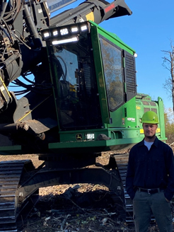 photo of Grant Erickson in front of logging equipment