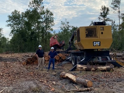 Two forestry men in front of Cat lumber machine