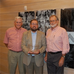 photo of 3 men, with one holding the RMS award